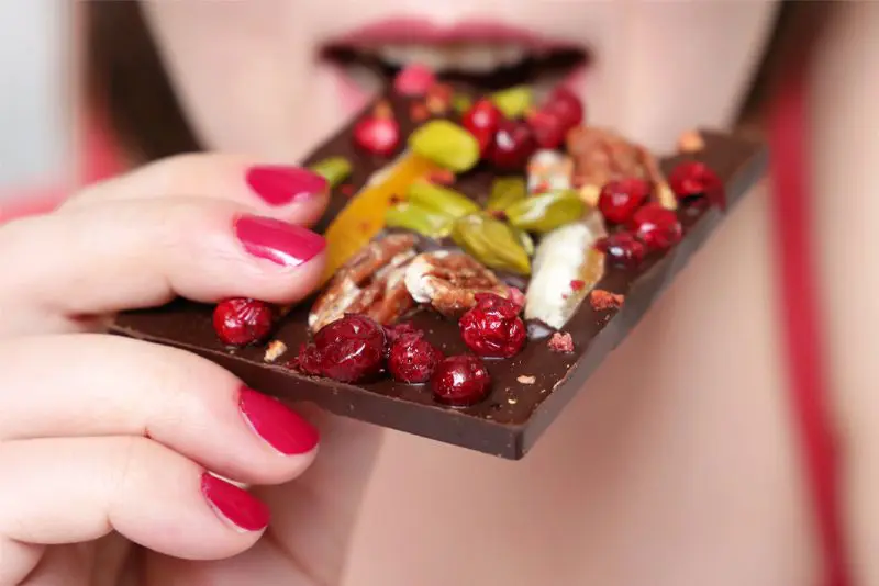 Woman-eating-chocolate-topped-with-dried-fruit