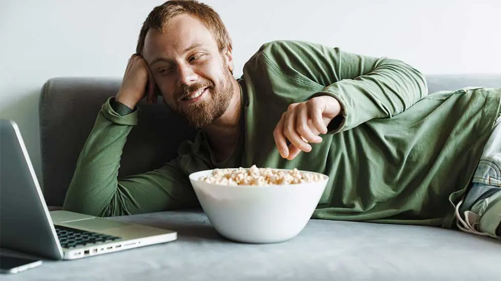A-man-lying-on-a-sofa-watching-an-internet-streaming-TV-show