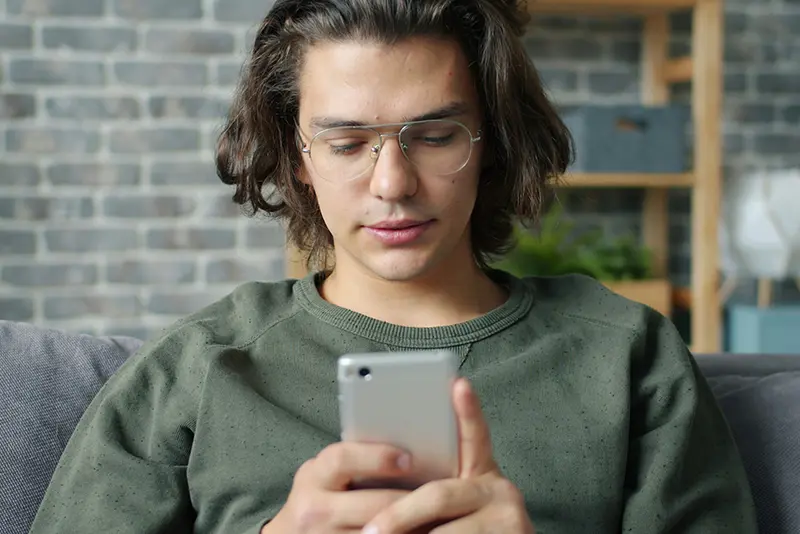 A-man-looking-at-his-smartphone-on-the-sofa